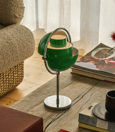 Lampă de masă Multi-Lite verde cu bază cromată pe o masă din lemn, lângă cărți.