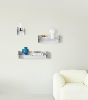 Rafturi de perete transparente Normann Copenhagen cu accesorii decorative într-un spațiu de locuit minimalist.